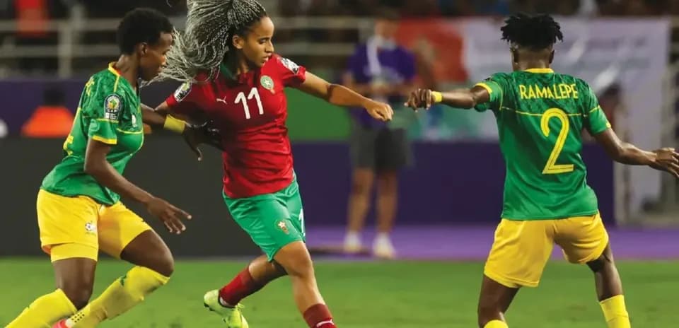 Morocco player dribbling past two opponents in match