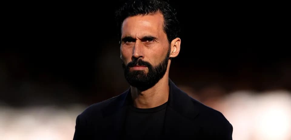 Bearded man in dark clothing looking serious