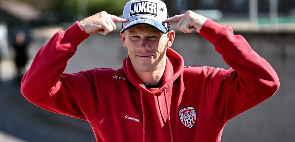 Shirted man pointing at 'JOKER' cap outdoors
