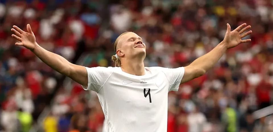 Futbolchi qo'llarini keng yoyib, maydonda turibdi