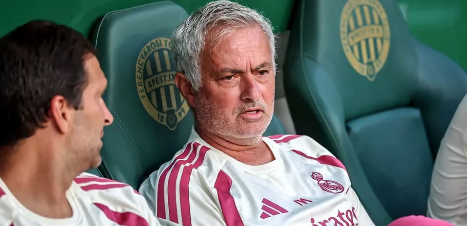 Mourinho sitting on bench with team staff