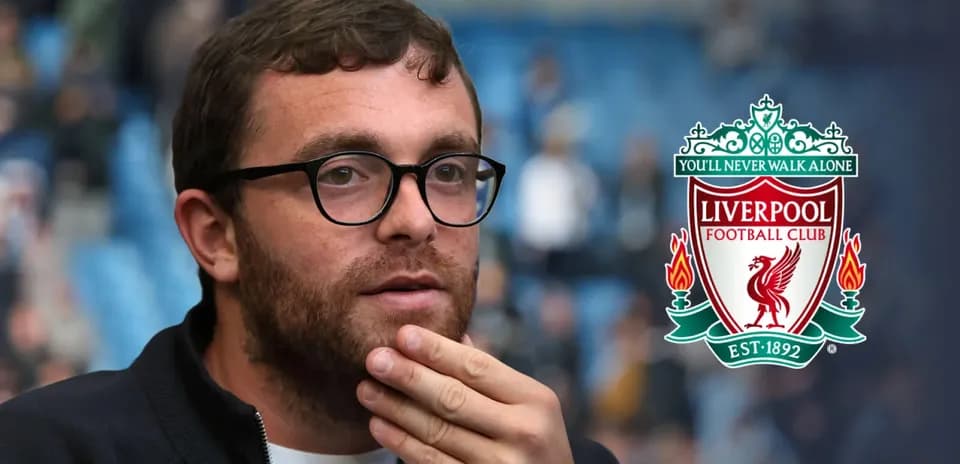 Shirted man with glasses near Liverpool FC logo