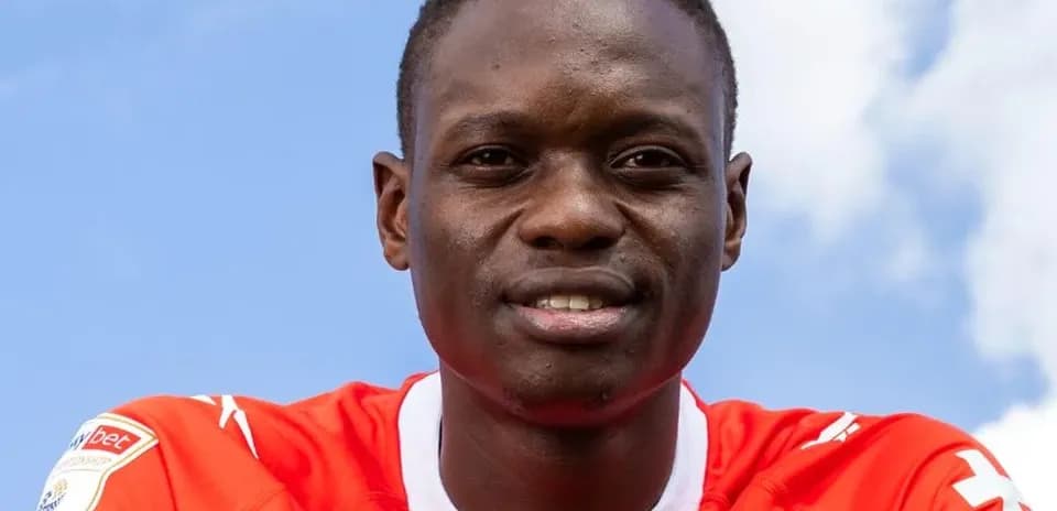 Futbolchi qizil forma kiygan, kulgili yuz ifodasi