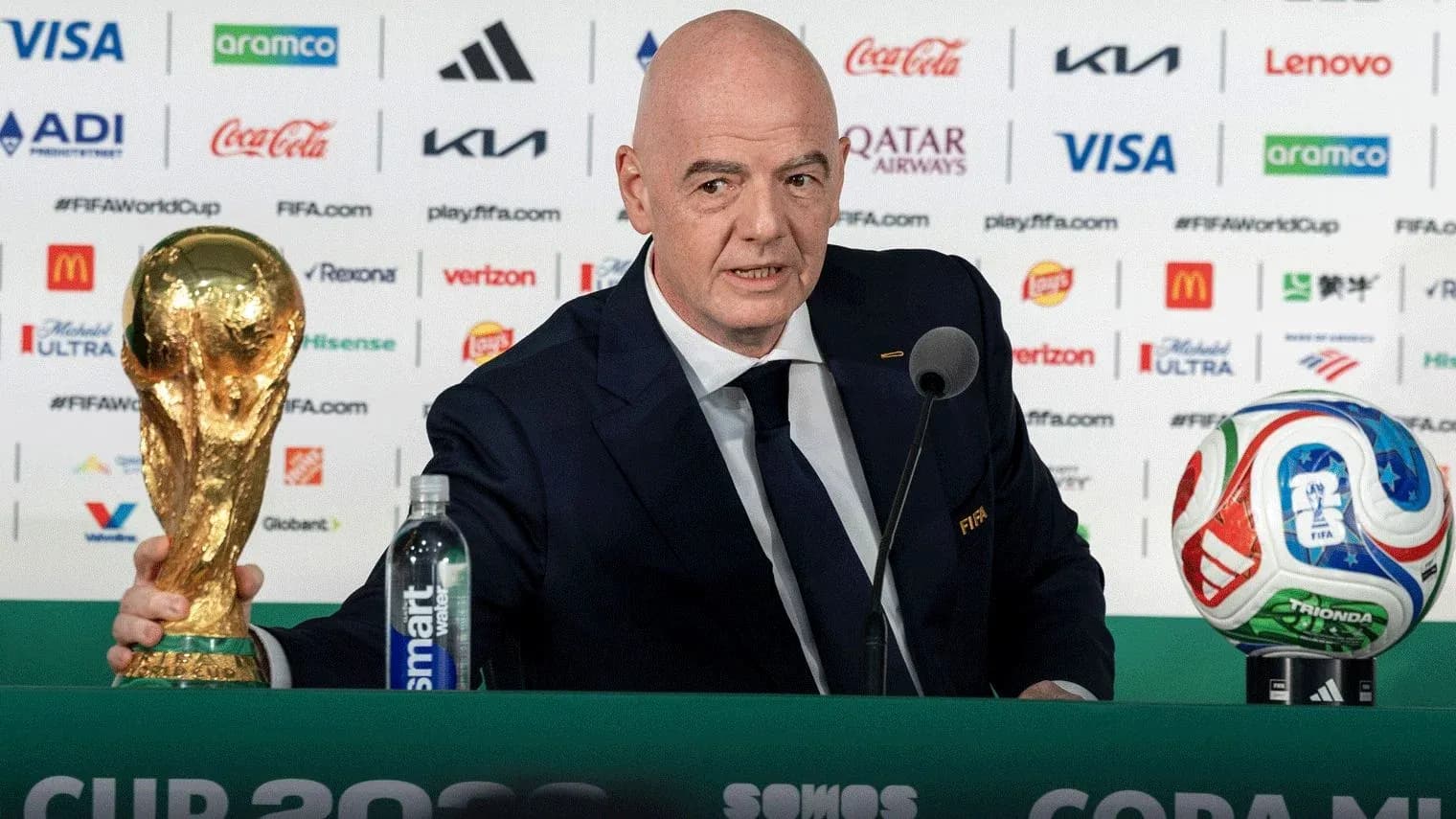 FIFA president holding World Cup trophy at podium