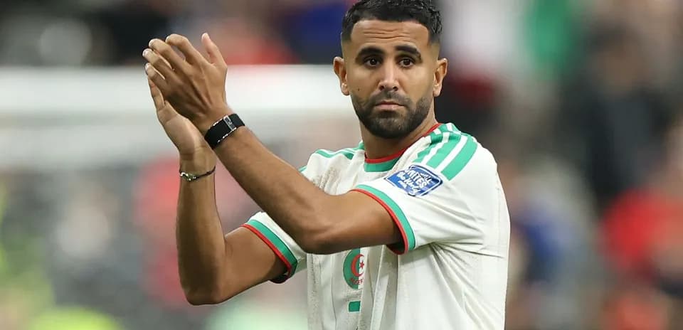 Futbolchi maydonda qo'llarini ko'tarib turibdi