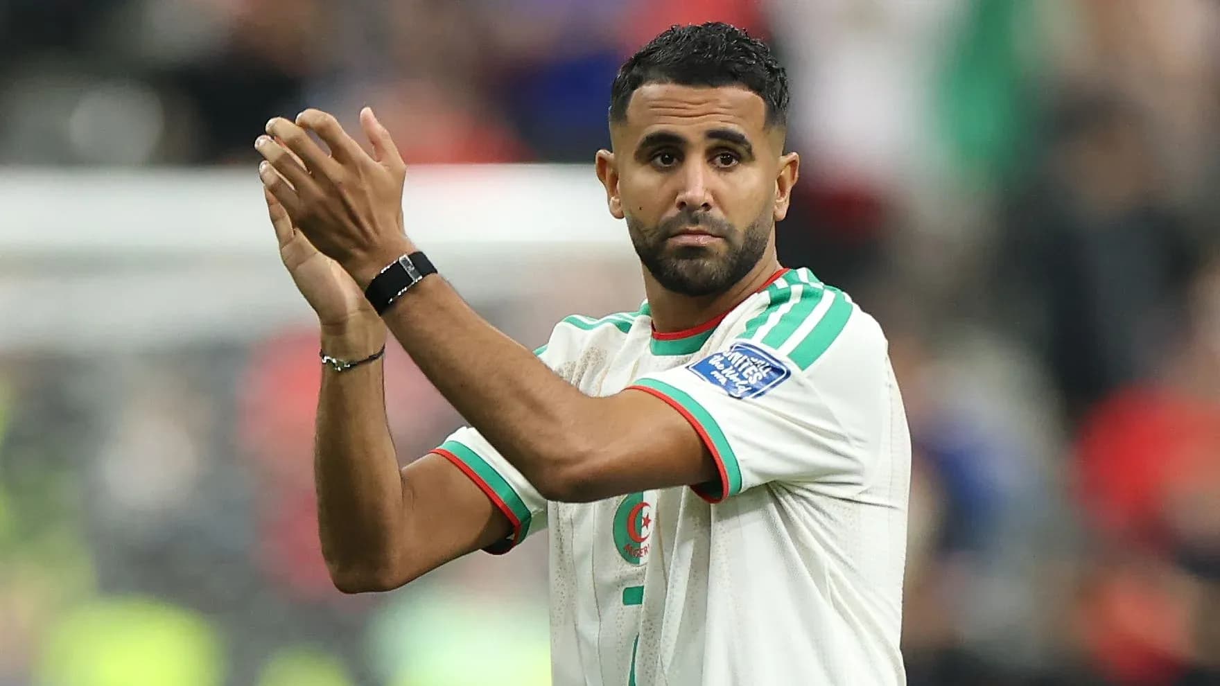 Futbolchi maydonda qo'llarini ko'tarib turibdi