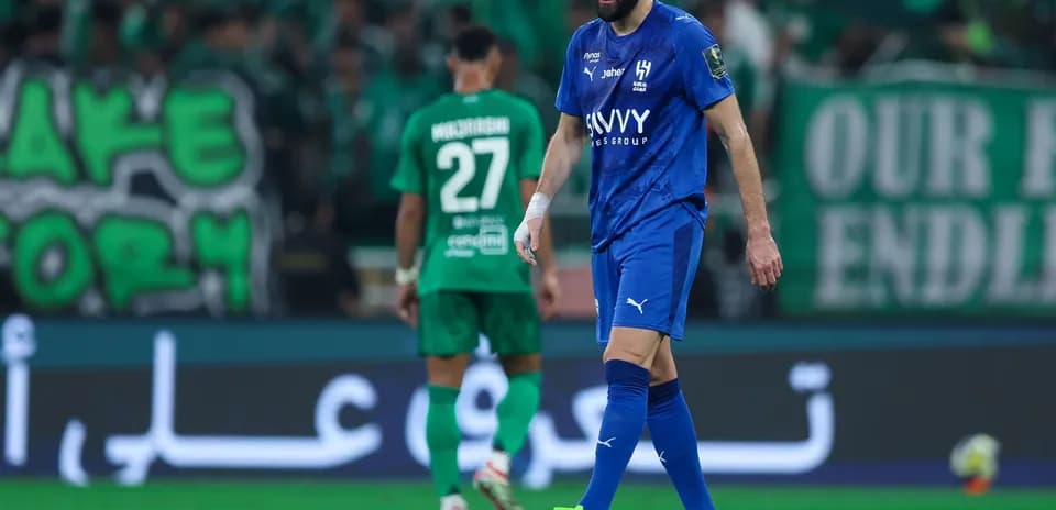 Futbolchilar maydonda harakat qilmoqda, tomoshabinlar ko'rinadi