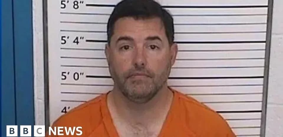 Man in orange jumpsuit at police station mugshot
