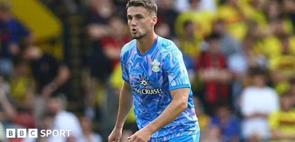 Futbolchi maydonda harakatda, tomoshabinlar ortida