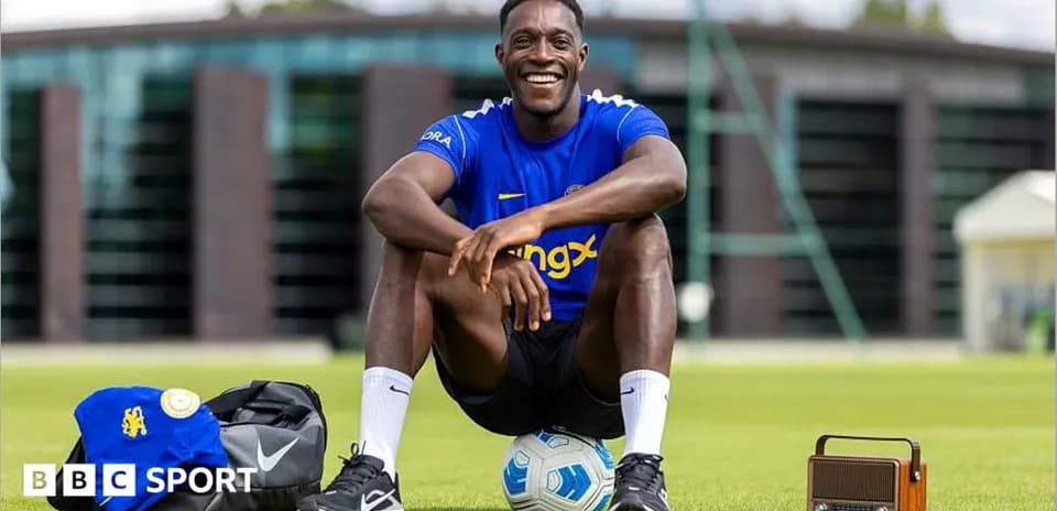 Futbolchi maydonda kulayotgan holda o'tirgan