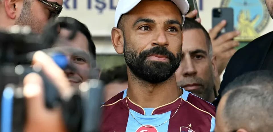 Futbolchi, jurnalistlar orasida turib, kameralar qarshisida
