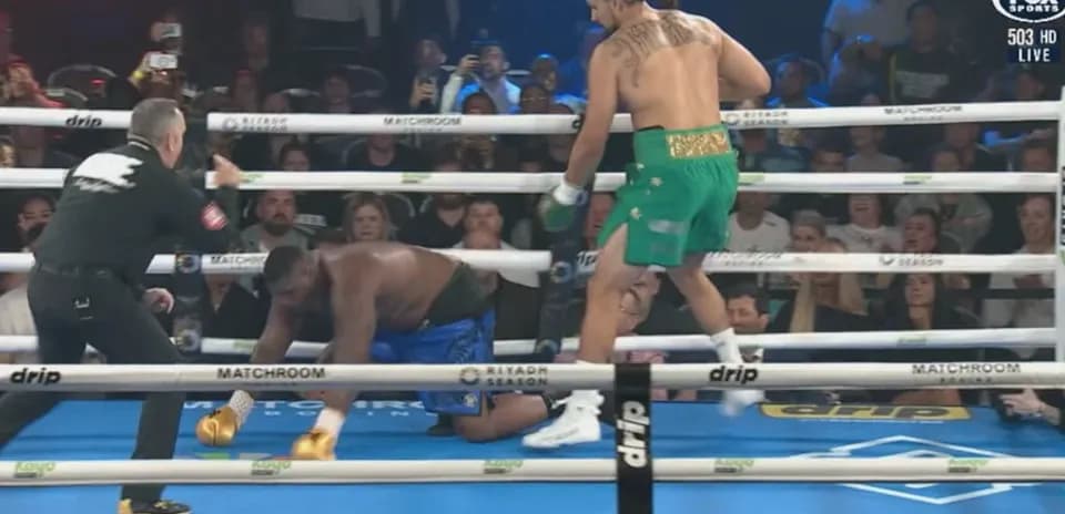 Boxer in green celebrates as opponent kneels