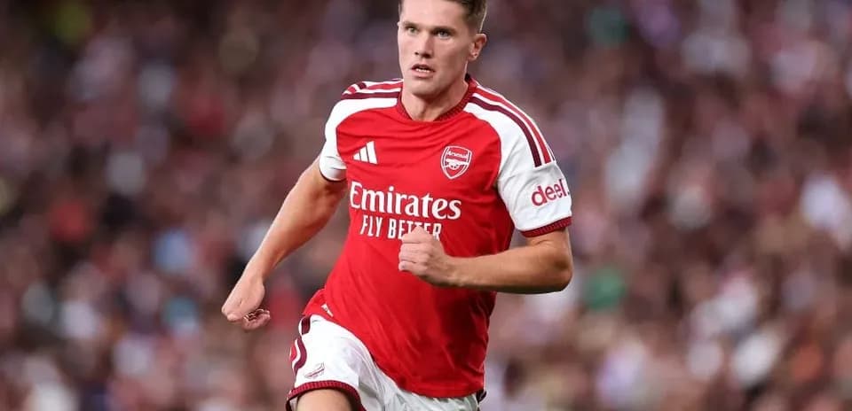 Futbolchi maydonda yugurayotgan Arsenal formasida