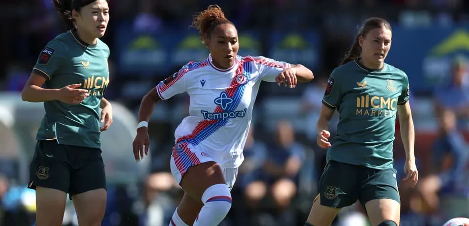 Three female football players competing for the ball