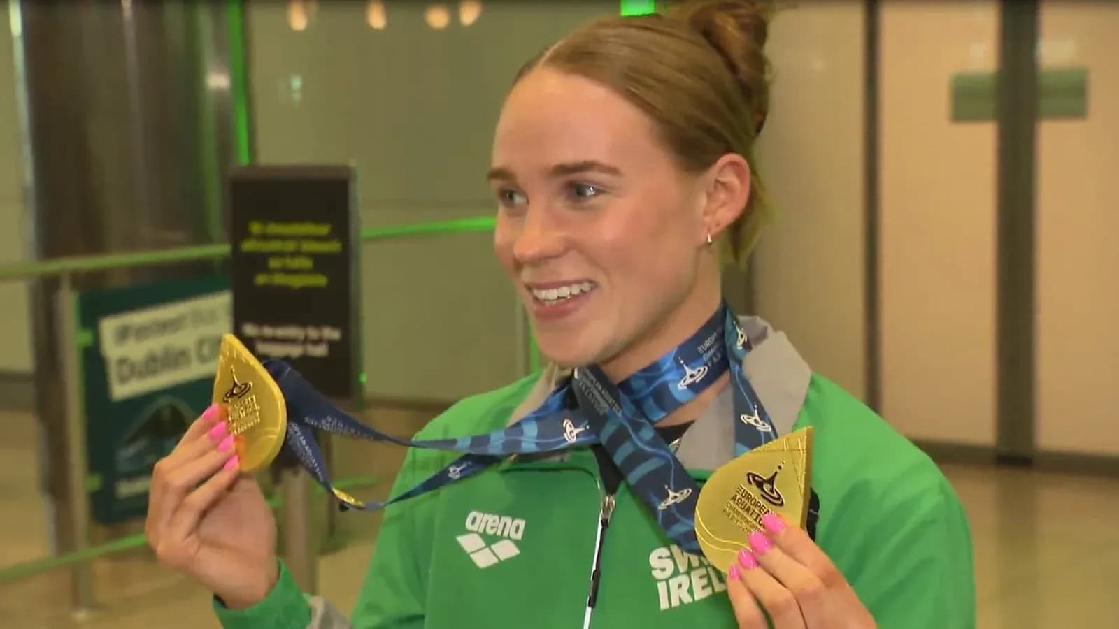 Athlete displaying gold medals at arrival terminal Athlete displaying gold medals at arrival terminal