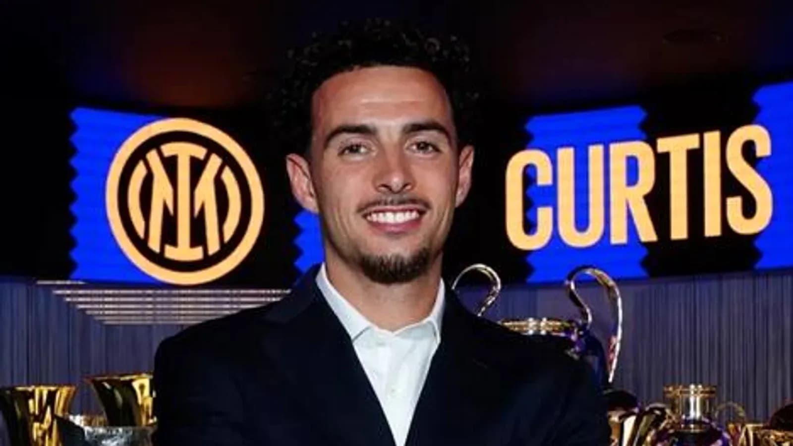Futbolchi Inter emblemi oldida tabassum qilmoqda Futbolchi Inter emblemi oldida tabassum qilmoqda
