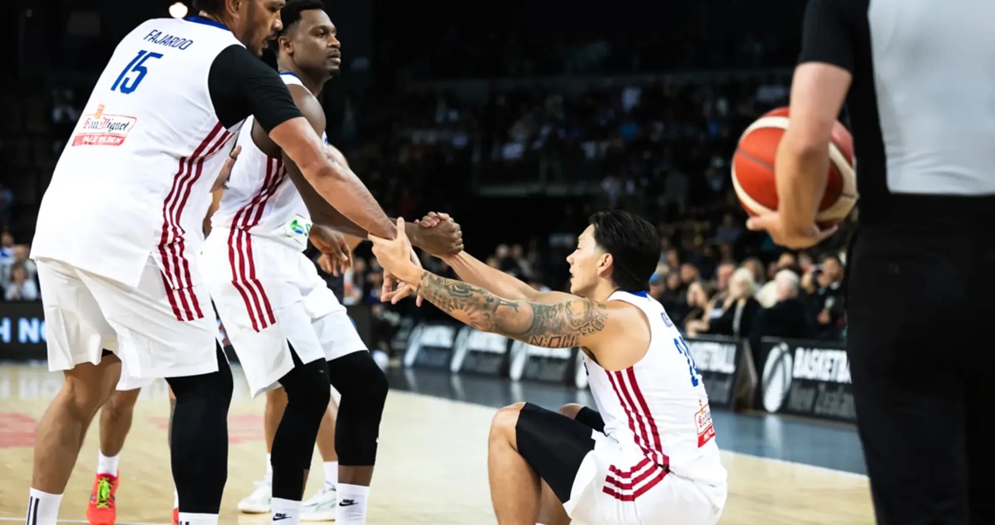 Two players assisting teammate sitting on court Two players assisting teammate sitting on court