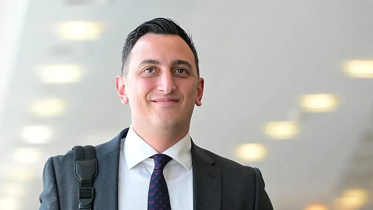 Man in suit smiling with bag over shoulder Man in suit smiling with bag over shoulder