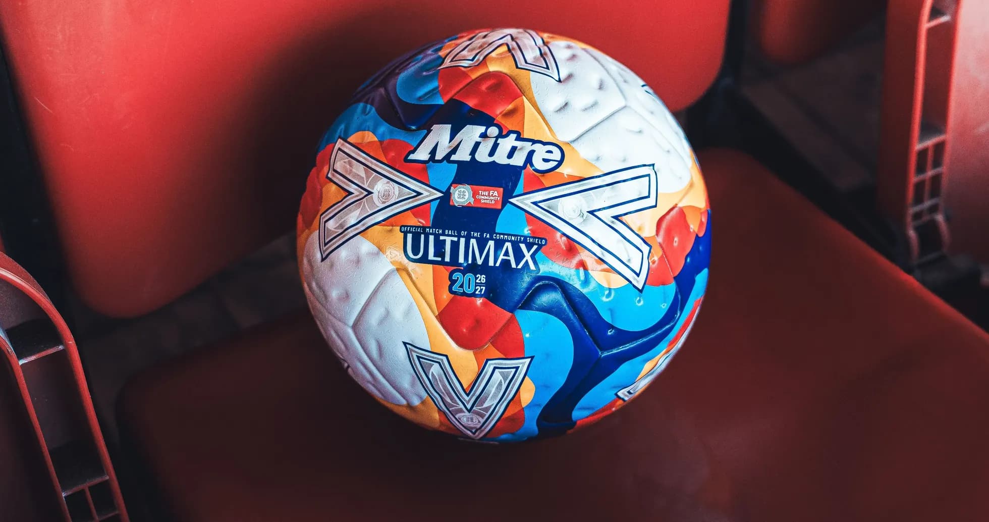 Mitre Ultimax football on red stadium seat Mitre Ultimax football on red stadium seat