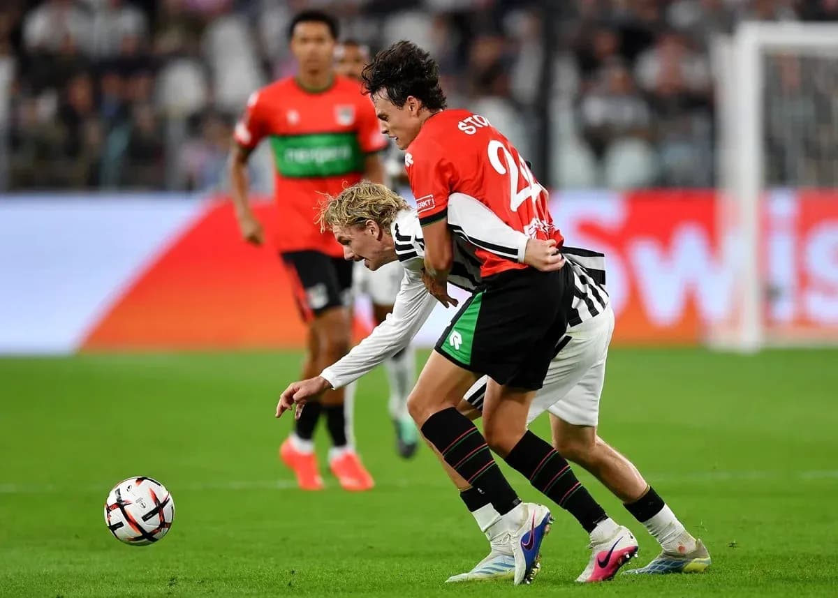 Two players battling for the ball on the pitch Two players battling for the ball on the pitch