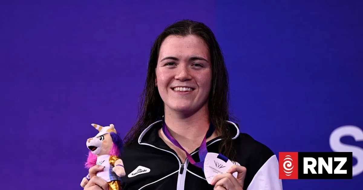 Sportsperson holding medal and plush toy at event Sportsperson holding medal and plush toy at event