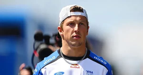 Driver in racing gear walking through paddock Driver in racing gear walking through paddock