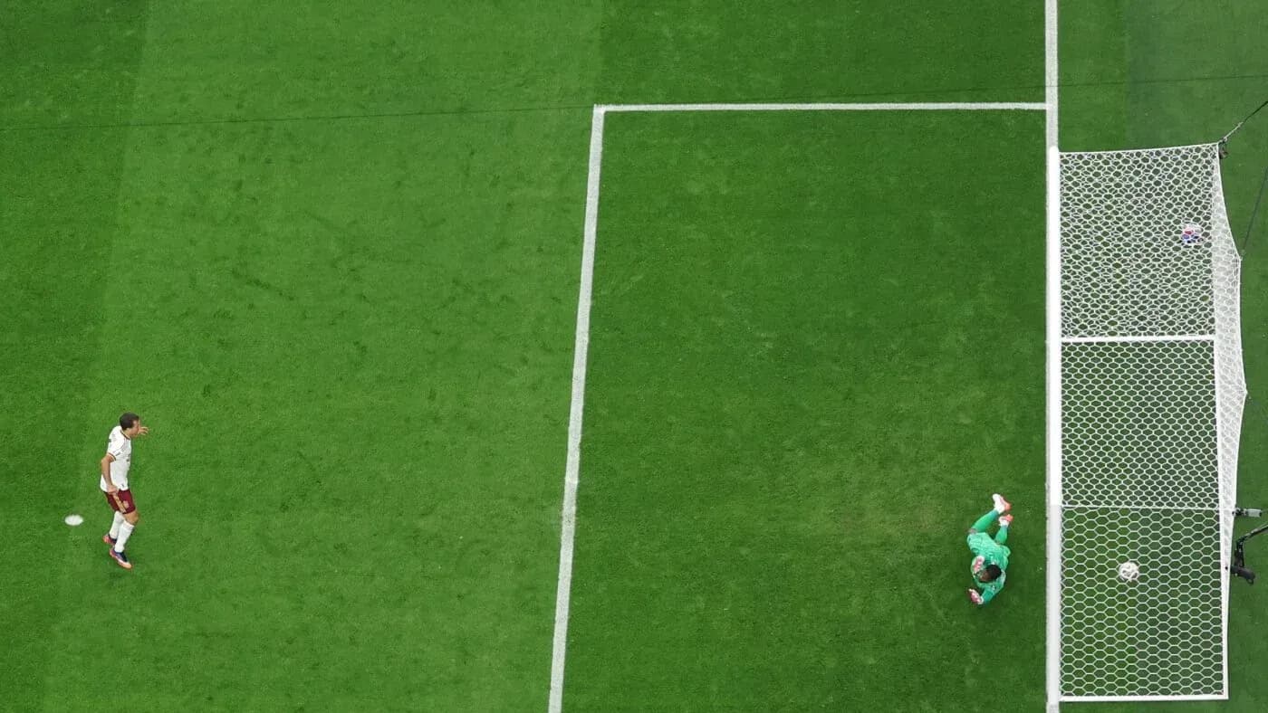 Player approaching goal while goalkeeper prepares to defend Player approaching goal while goalkeeper prepares to defend