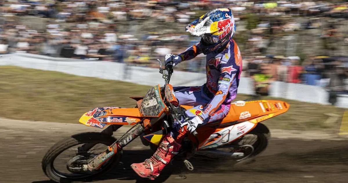 Motocross rider navigating dirt track with spectators Motocross rider navigating dirt track with spectators
