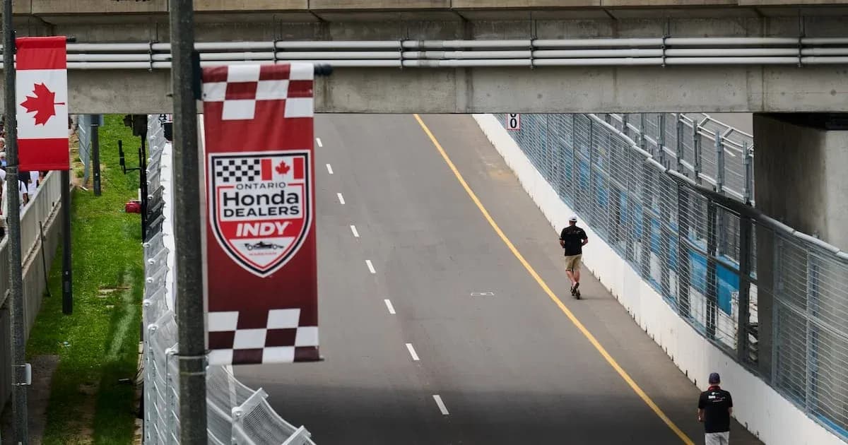 Person walking on racetrack near banners Person walking on racetrack near banners