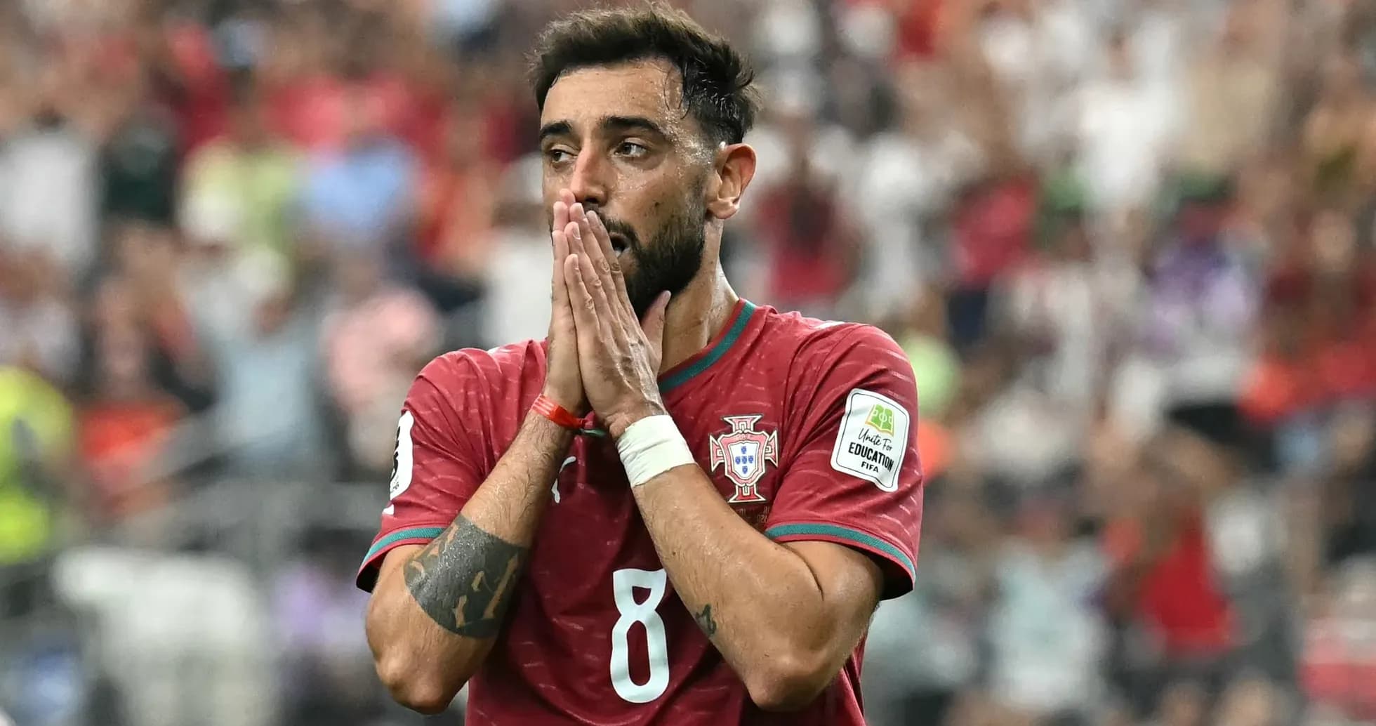 Portugaliya futbolchisi o'yin davomida qo'llarini yuqoriga ko'targan Portugaliya futbolchisi o'yin davomida qo'llarini yuqoriga ko'targan
