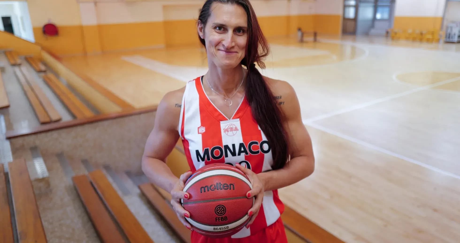 Basketball player holding ball in gymnasium Basketball player holding ball in gymnasium