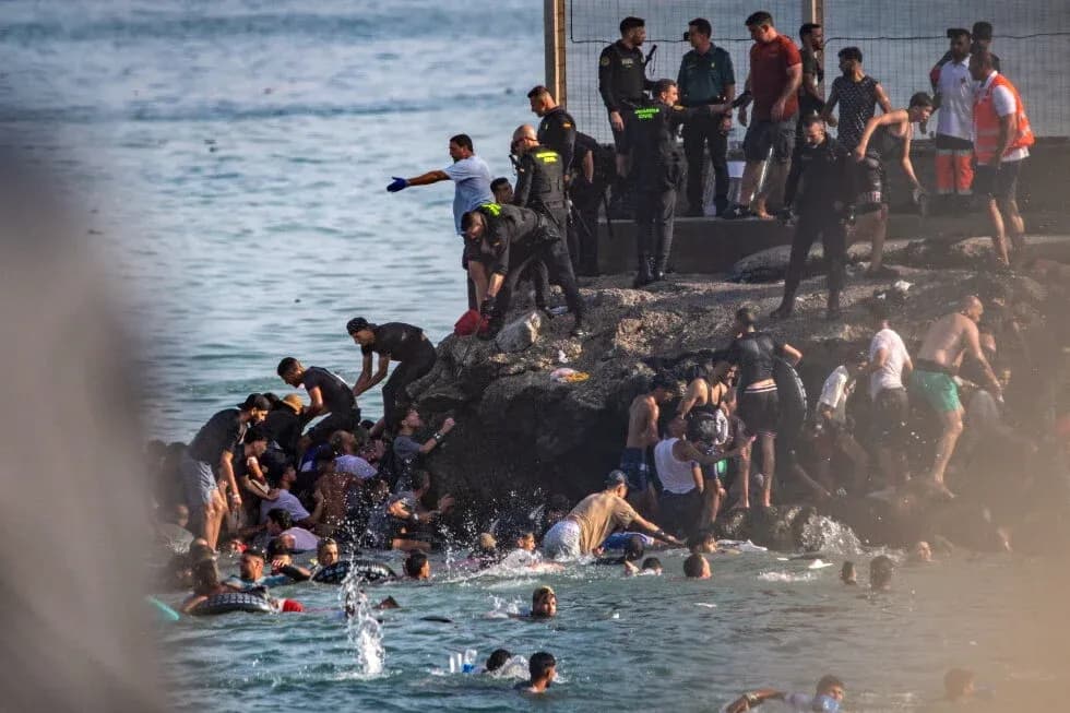 People in water near rocky shore with authorities present People in water near rocky shore with authorities present