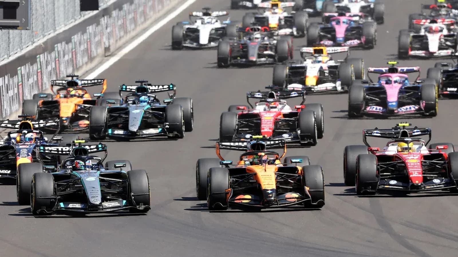 Formula 1 cars racing closely on track Formula 1 cars racing closely on track