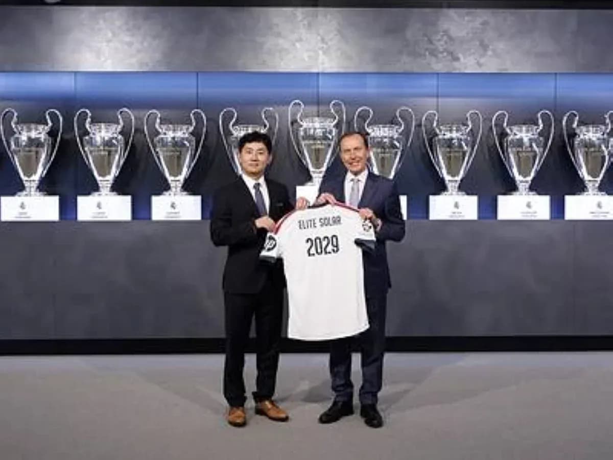 Two men holding jersey in front of trophies Two men holding jersey in front of trophies