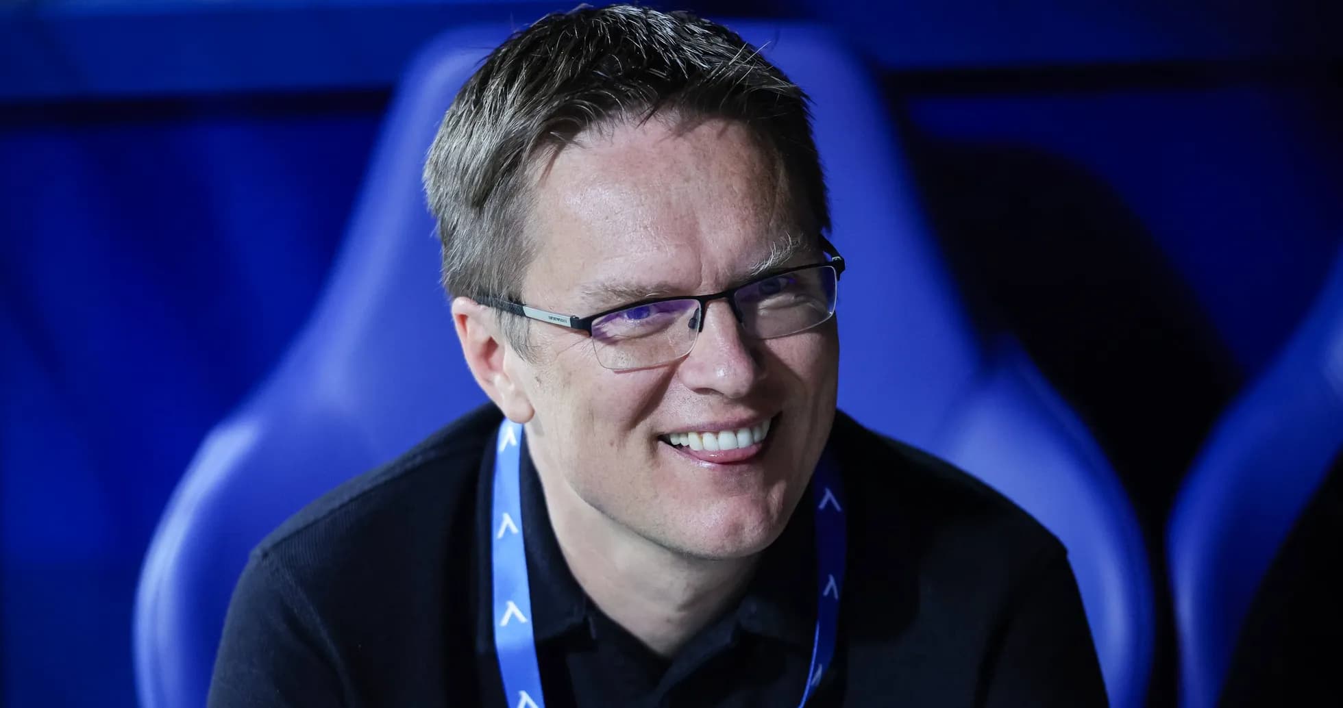 Man smiling in a sports venue seating area Man smiling in a sports venue seating area